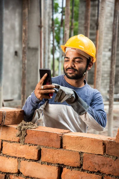 Stock image Happy smiling young indian construction labour busy on mobile phone at workplace