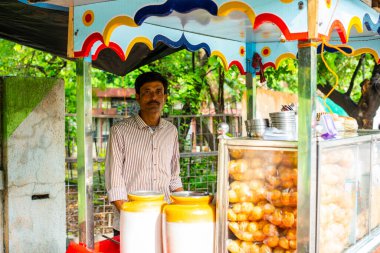 panipuri mağazası - mutlu genç Hintli erkek yol kenarı satıcısı golgappe satıyor