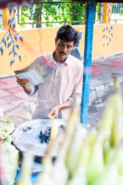 Hintli sokak satıcısı kavrulmuş mısır veya bhutta satıyor.