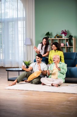 Neşeli Hintli aile evde akıllı telefon kullanırken eğleniyor.