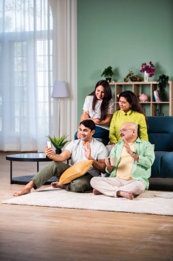 Neşeli Hintli aile evde akıllı telefon kullanırken eğleniyor.