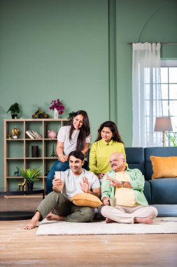 Neşeli Hintli aile evde akıllı telefon kullanırken eğleniyor.