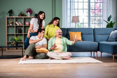 Neşeli Hintli aile evde akıllı telefon kullanırken eğleniyor.