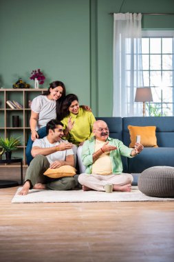 Neşeli Hintli aile evde akıllı telefon kullanırken eğleniyor.