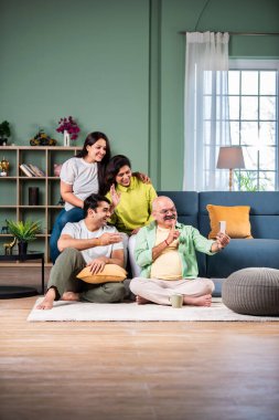 Neşeli Hintli aile evde akıllı telefon kullanırken eğleniyor.