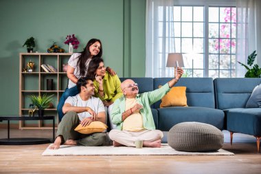 Neşeli Hintli aile evde akıllı telefon kullanırken eğleniyor.