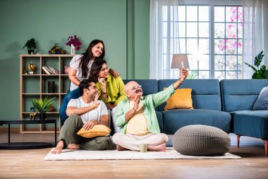 Neşeli Hintli aile evde akıllı telefon kullanırken eğleniyor.