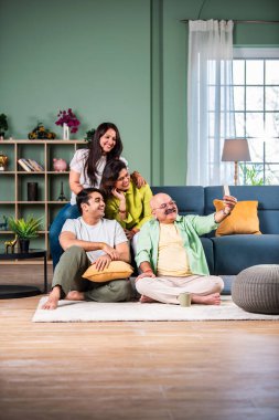 Neşeli Hintli aile evde akıllı telefon kullanırken eğleniyor.