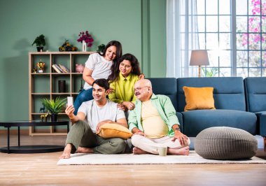 Neşeli Hintli aile evde akıllı telefon kullanırken eğleniyor.