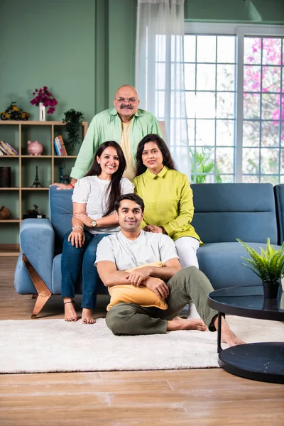Indian family of four posing for a group photo in living room at modern home