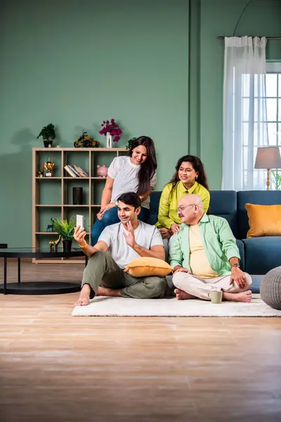 Neşeli Hintli aile evde akıllı telefon kullanırken eğleniyor.