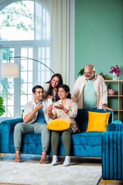 Neşeli Hintli aile evde akıllı telefon kullanırken eğleniyor.