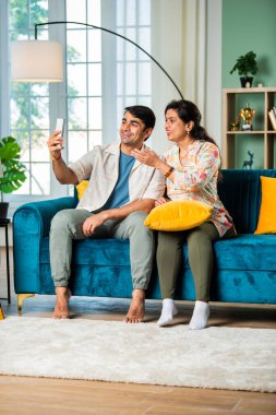 Küçük oğlu olan Hintli yaşlı bir anne video görüşmesi veya oto portre için akıllı telefon kullanıyor.