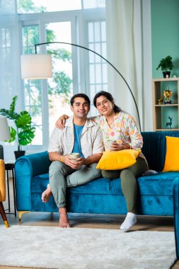 Yakışıklı genç Hintli adam ve yaşlı anne evde kahve içiyorlar.