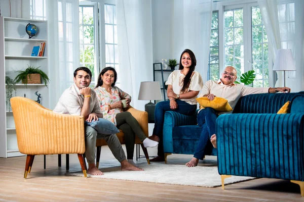 Indian family of four posing for a group photo in living room at modern home