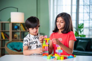 Küçük şirin Hintli çocuklar evlerinde tahta oyuncaklarla oynuyorlar.