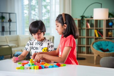 Küçük şirin Hintli çocuklar evlerinde tahta oyuncaklarla oynuyorlar.