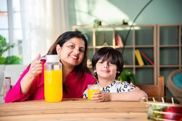 Indian little kid with mother having fresh juice at home
