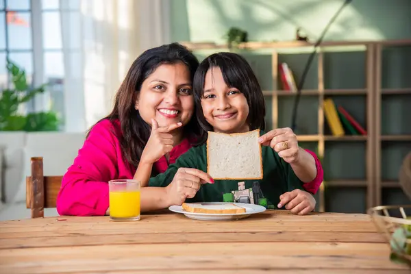 Cute little Indian asian kids holding up a slice of bread with a cut out smiley face