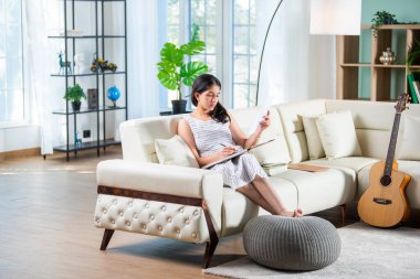 Evde kanepede otururken, Hintli genç bir kadın günlük ya da günlük yazıyor.