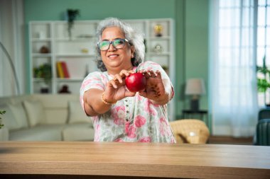 sağlıklı beslenme konsepti. Hintli son sınıf öğrencisi kadın elma gösteriyor.
