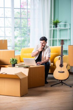 Elinde karton kutularla koltukta oturan Hintli bir adam, dizüstü bilgisayar ya da akıllı telefondan kiralık ev arıyor.