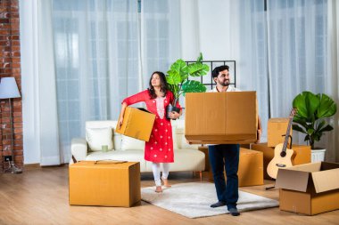 Hintli genç çift yeni evlerinde kutu taşıyorlar.