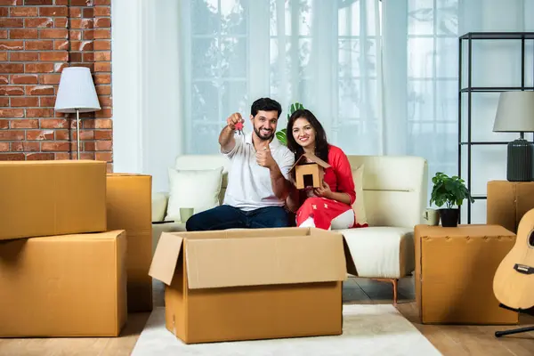 Indian couple and home moving concept with piggy bank and cardboard boxes