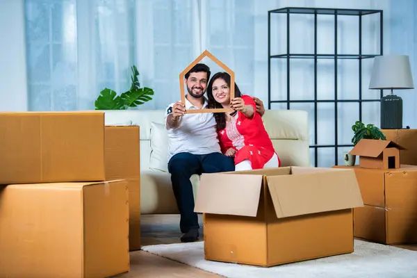 Indian couple and home moving concept with piggy bank and cardboard boxes