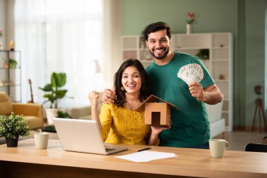 Hintli genç çift finans, ev satın alma hesapları para fan ve laptop ile