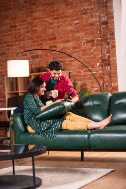 Hintli genç çift evde akıllı telefon kullanıyor.