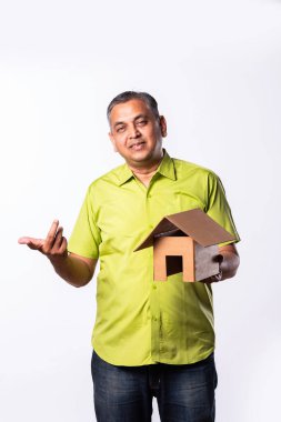 Hintli orta yaşlı adam kartondan ev tutarken düşünüyor.