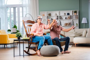 Evde televizyon izleyen gri saçlı Hintli orta yaşlı çift.