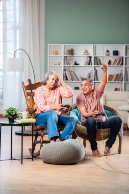 Orta yaşlı Hintli çift video oyunları oynarken eğleniyor.