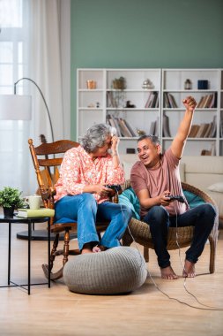 Orta yaşlı Hintli çift video oyunları oynarken eğleniyor.