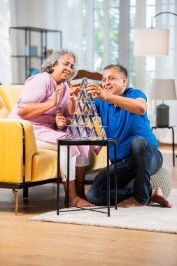 Hintli orta yaşlı çift iskambil oynayarak ve eğlenerek ev inşa ediyor.