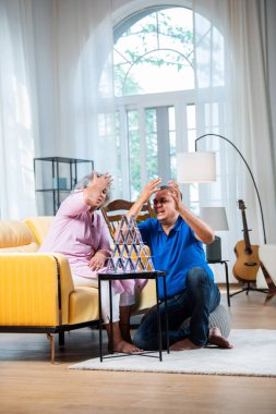 Hintli orta yaşlı çift iskambil oynayarak ve eğlenerek ev inşa ediyor.