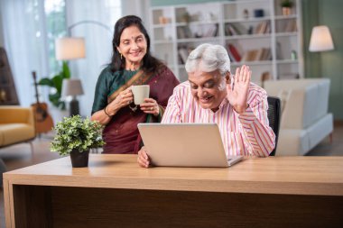 Yetişkin Hintli çift evde dizüstü bilgisayarda internette sörf yapıyor.
