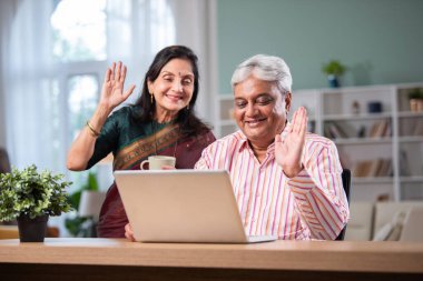 Yetişkin Hintli çift evde dizüstü bilgisayarda internette sörf yapıyor.