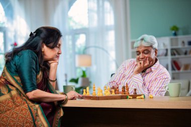 Hintli üst düzey bir çift evde masada satranç oynuyor.