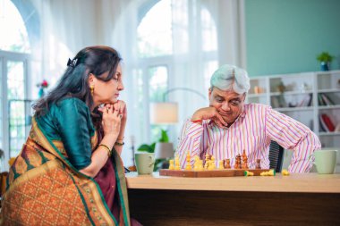 Hintli üst düzey bir çift evde masada satranç oynuyor.