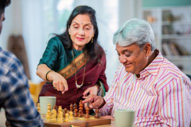 Hintli üst düzey bir çift evde masada satranç oynuyor.