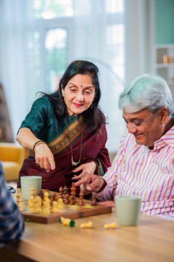 Hintli üst düzey bir çift evde masada satranç oynuyor.