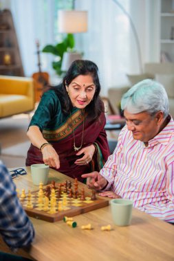 Hintli üst düzey bir çift evde masada satranç oynuyor.