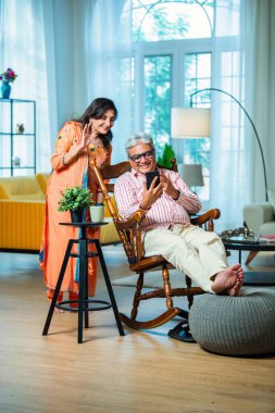 Hintli emekli çift evde akıllı telefon kullanıyor.