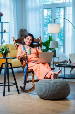 Evde dijital tablet ya da dizüstü bilgisayar kullanan yaşlı Hintli kadın. Teknoloji kavramı ve yaşlılar.