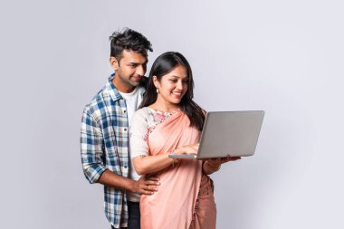 Hintli evli genç çift dizüstü bilgisayar kullanıyor.