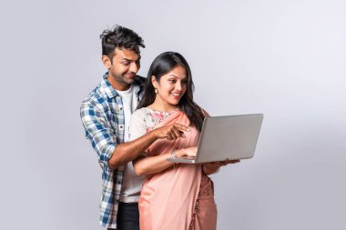 Hintli evli genç çift dizüstü bilgisayar kullanıyor.