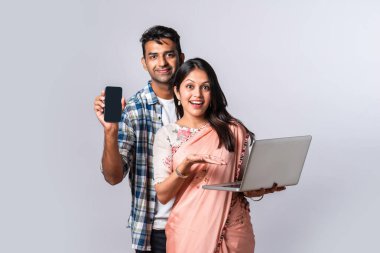 Hintli evli genç çift dizüstü bilgisayar kullanıyor.