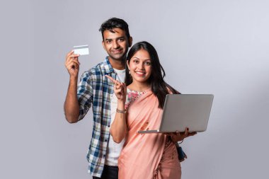 Hintli evli genç çift dizüstü bilgisayar kullanıyor.